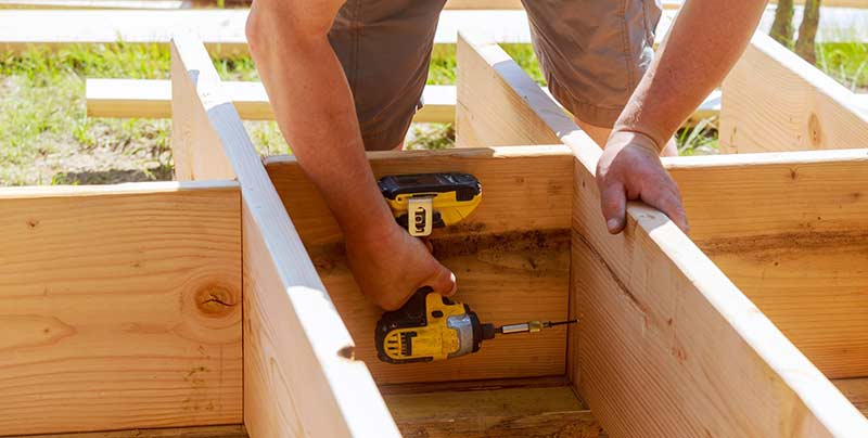 Full-length-of-carpenter-drilling-wood-at-construction-patio